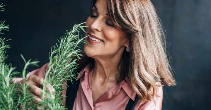 an old woman smelling a lavender plant