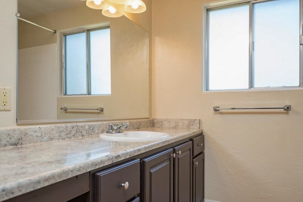 Granite style counters in the bathroom with a large mirror above the vanity at Gateway Village in Springfield, Oregon