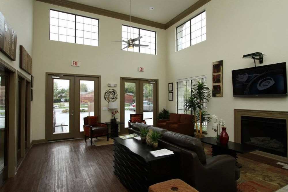 Bright community lounge with large windows, comfortable seating, and modern decor at Villa Del Prado in Houston, Texas