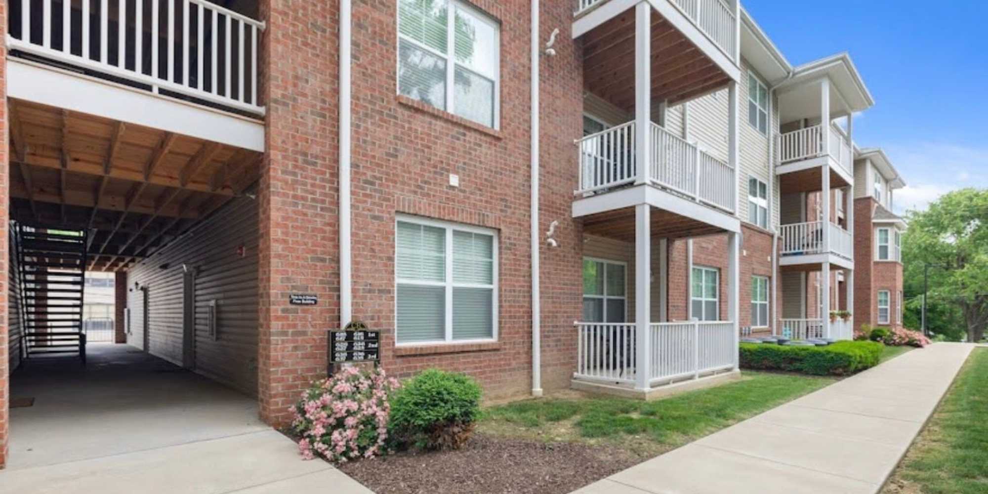 Brick apartment building with balconies, landscaped gardens, and a clear pathway leading to the entrance at Castle Ridge Apartments in Pittsburgh, Pennsylvania