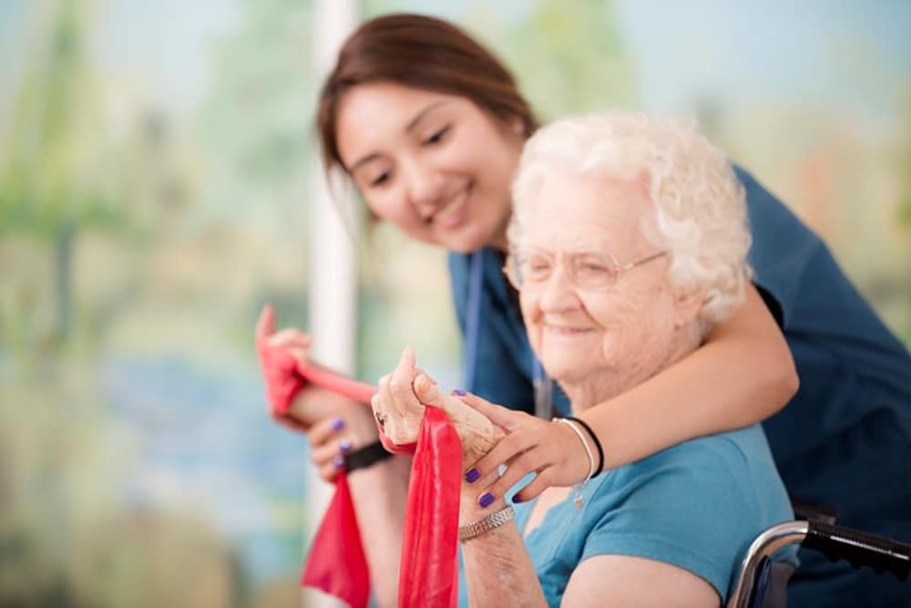 A caretaker helping a resident with strength training at The Mansions at Gwinnett Park Assisted Living and Memory Care in Lawrenceville, Georgia