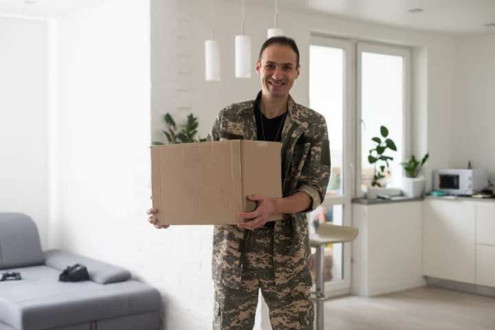 Service member carrying a box while packing for deployment