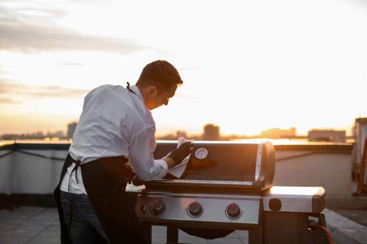 Man wiping his grill down before covering for storage
