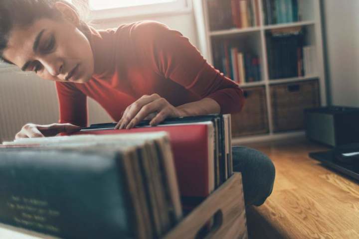 Woman looking through vinyl collection in a wooden crate