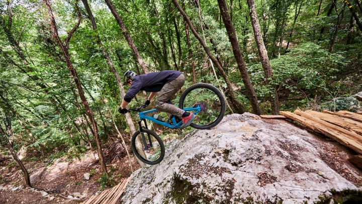 Person mountain biking down a trail in a wooded area