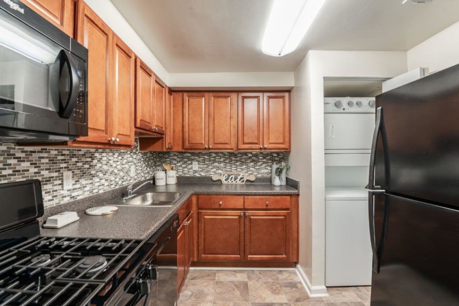 Kitchen with maple cabinets, black appliances, and in-unit laundry at Lighthouse at Twin Lakes Apartment Homes in Beltsville, Maryland