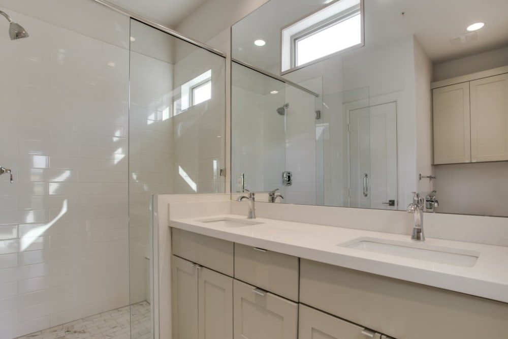 Apartment bathroom with double sink vanity and large mirror at The Collection Townhomes in Dallas, Texas