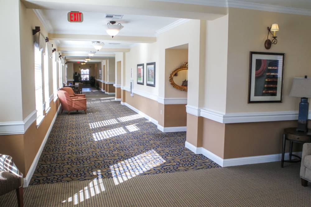 A large, carpeted hallway with a comfy chair at Isle at Raider Ranch in Lubbock, Texas