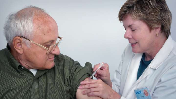 Senior man getting his flu shot from a nurse