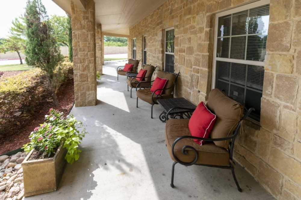 Cheerful seating area outside with red cushions at Lakeshore Assisted Living and Memory Care in Rockwall, Texas