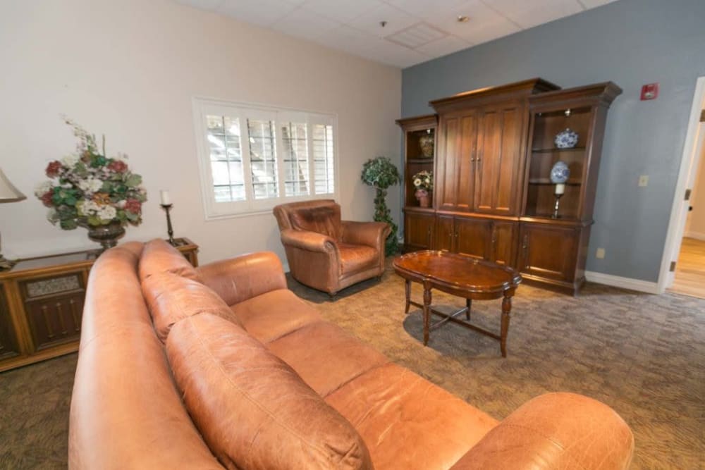 Sitting area with plush couch and wood furniture at The Grand Court Senior Living in Mesa, Arizona