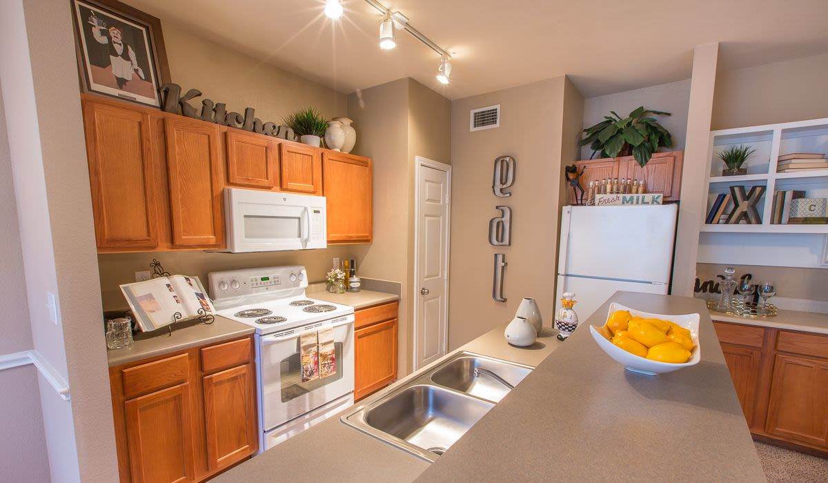  Well-lit modern kitchen with stove, microwave, oven, refrigerator, sink and wooden storage cabinets at Cobblestone Park in Manvel, Texas