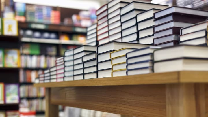 A low view of a stack of books in a bookstore in Albuquerque set up on a wood table with a shallow depth of field