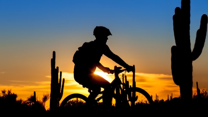 Silhouette of a man riding a bike at sunset