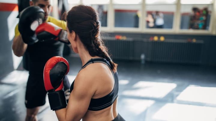 A woman is practicing kickboxing classes in Tampa with her male coach
