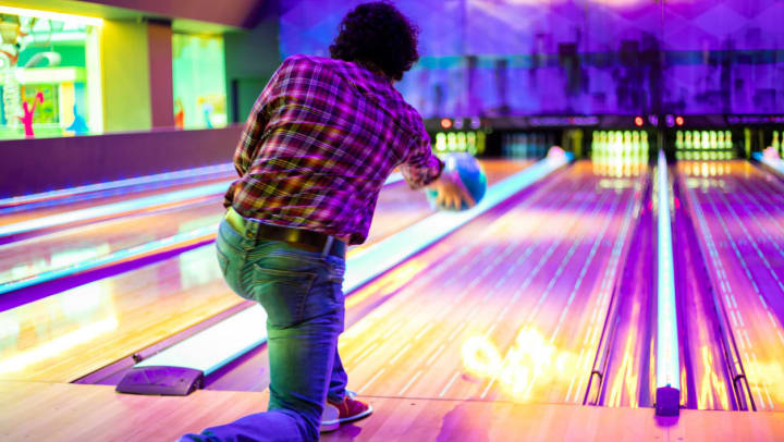 Man bowling under neon lights at a bowling alley around Chandler