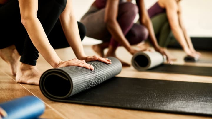 Three people rolling their yoga mats during a class at a Keller studio.