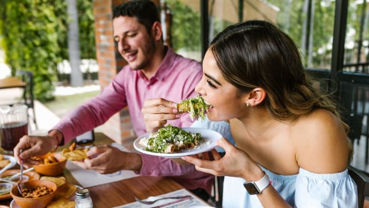 A woman taking a bite of taquitos | Mexican restaurants in Brunswick