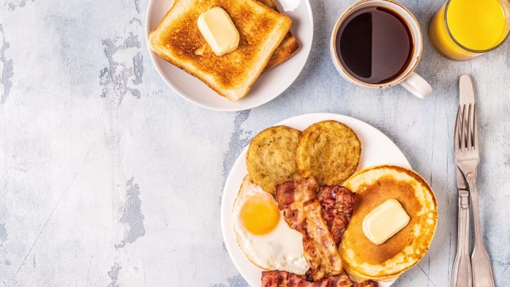 A table with two plates of breakfast foods beside cups of coffee and orange juice │ breakfast restaurants in Keller