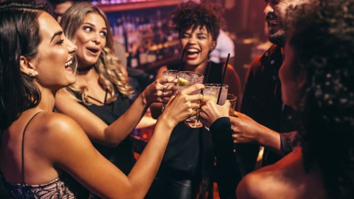 Group of friends partying in a nightclub and toasting drinks.