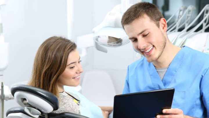 A young woman at the dentist reviewing information with her male hygienist | dental clinics around Jacksonville