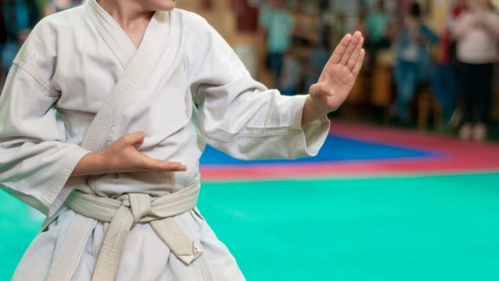 Man in a karate stance with hands raised in front of an audience