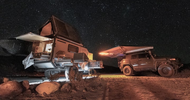 Open camper and SUV vehicle under the stars at night