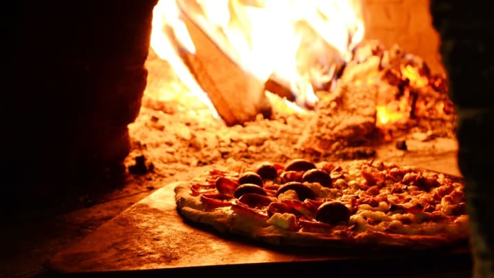 A delicious pizza cooking in a wood-fired oven at a restaurant near Olympus Waterford in Keller, Texas.   
