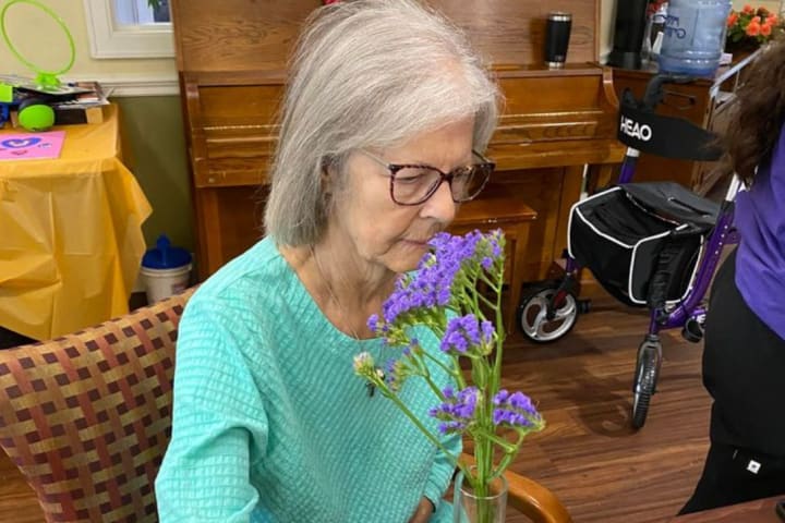 A resident flower arranger stops to smell the blooms at Chisholm Place Memory Care in Wichita Kansas