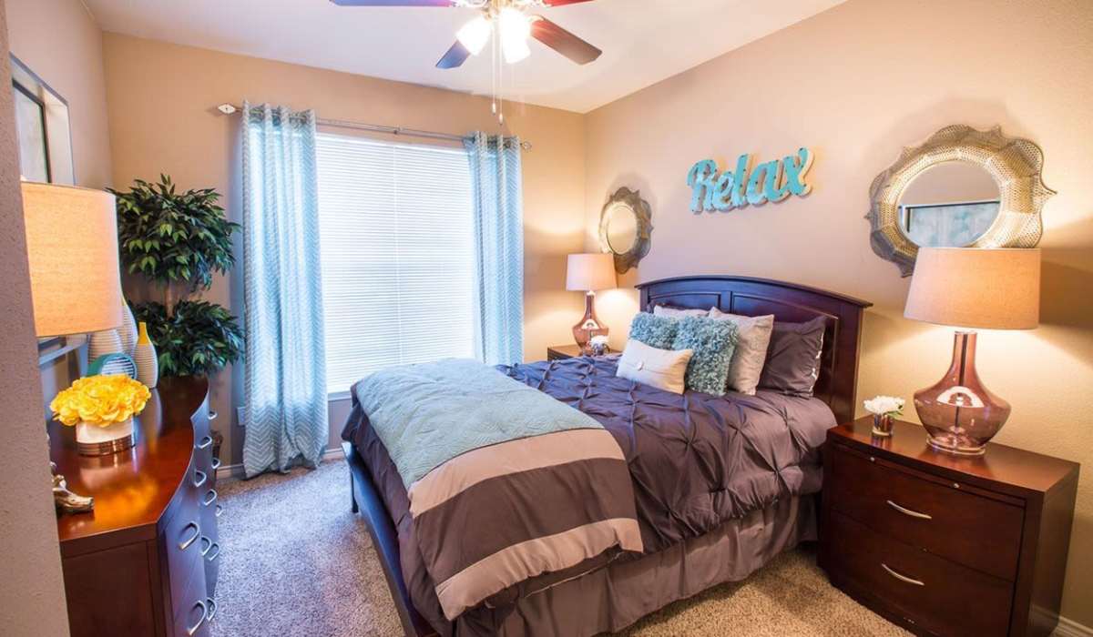 Spacious bedroom with comfortable bed, plush carpet, large windows and wooden furniture at Cobblestone Park in Manvel, Texas