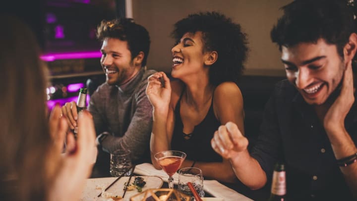 a group of friends laughing while enjoying dinner | comedy clubs around Tampa
