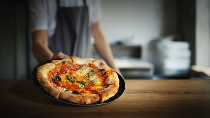 A pizza chef shows off freshly made pizza | pizza restaurants in Brunswick