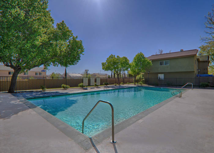 Swimming pool area on a beautiful day at Woodlands West Apartment Homes in Lancaster, CA