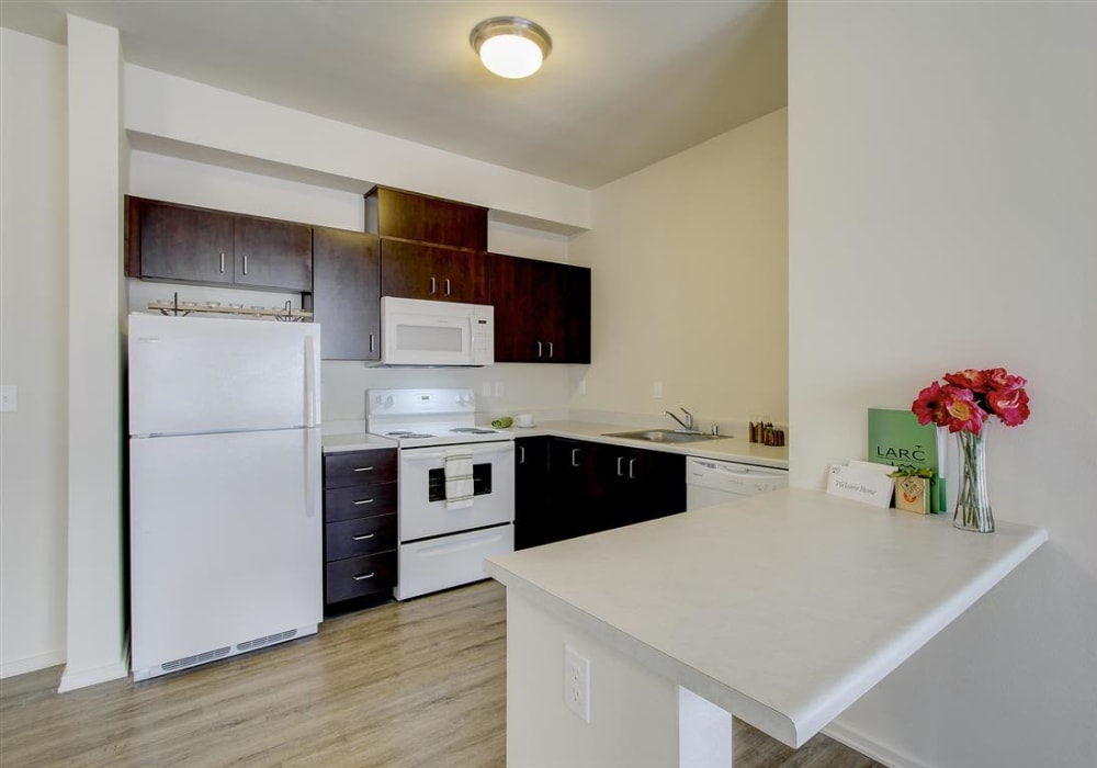 Spacious kitchen with white appliances and wooden cabinetry at LARC at Kent in Kent, Washington