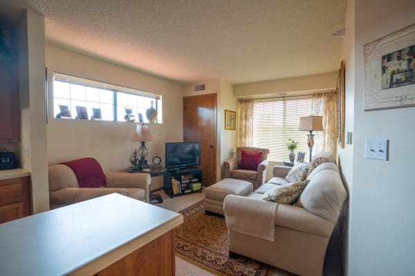 Senior resident aparment living room with furniture and large windows at Meadows on Fairview in Wyoming, Minnesota