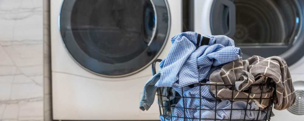 In home washer dryer facility with a laundry basket in front of it at The Miller in Tacoma, Washington