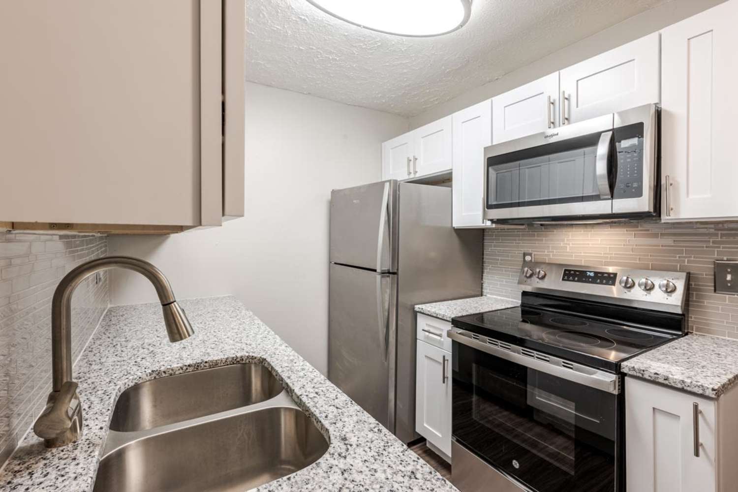 Renovated kitchen with stainless steel appliances, white cabinets, and granite countertops at Lakeshore Drive in Cincinnati, Ohio