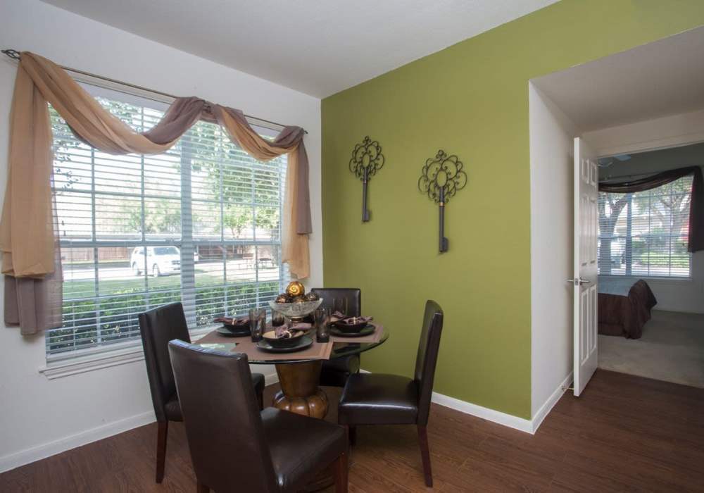 Cozy dining area with wood-style flooring, round table, and large window with natural light at Rincon Apartments in McAllen, Texas