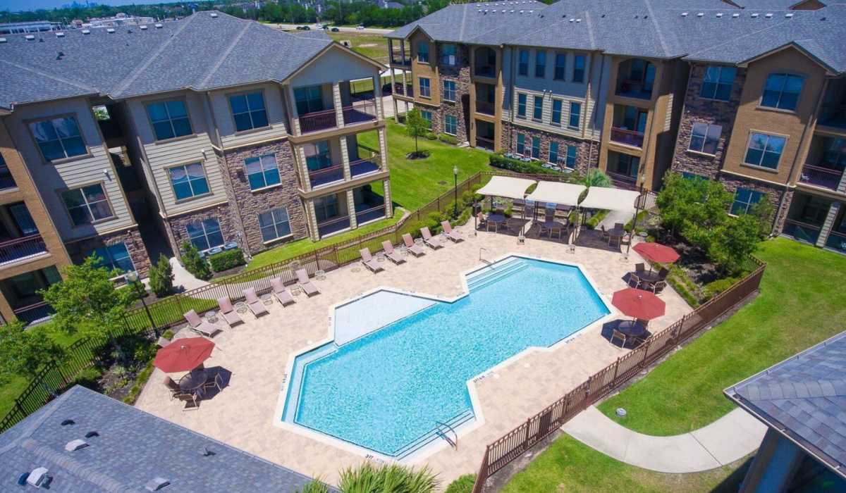 Resort style swimming pool with sun loungers at Cobblestone Park in Manvel, Texas