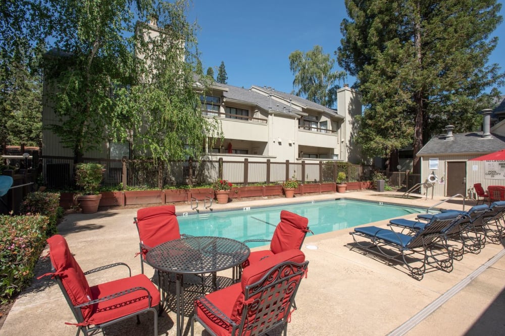 Pool area with tables and chairs at Huntcliffe Apartments in Fair Oaks, California