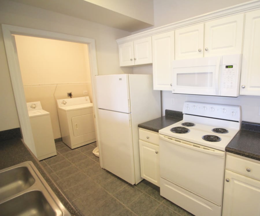 Full-size in-unit washer and dryer next to the kitchen of a model home at Timber Lakes Apartment Homes in Kansas City, Missouri