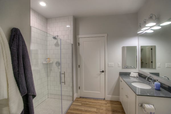 Bathroom with tiled shower and granite countertop in model home at District Lofts in Gilbert, Arizona