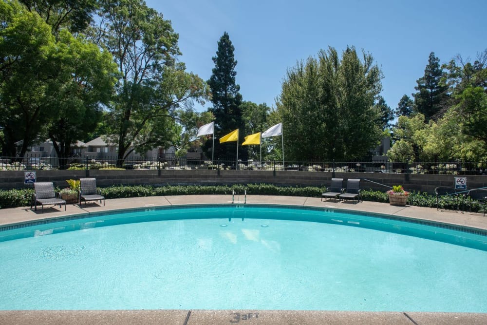 Swimming pool with chairs at Zinfandel Ranch Apartments in Rancho Cordova, California