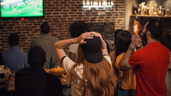 Group of people from behind watching sports in a restaurant