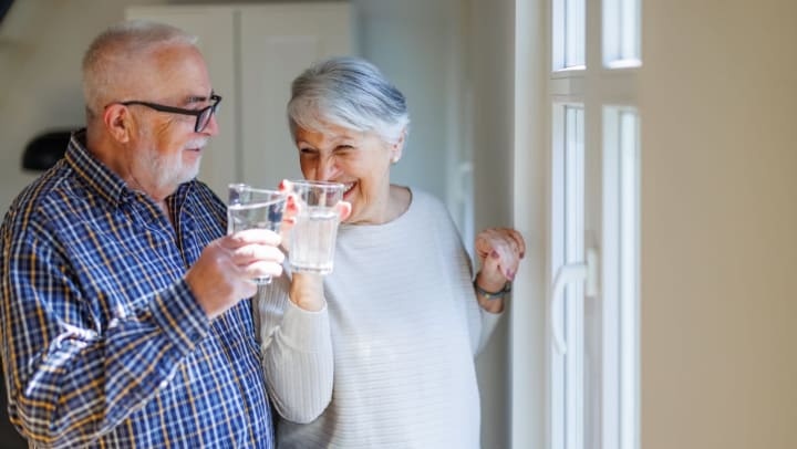 Two seniors clinking water glasses 