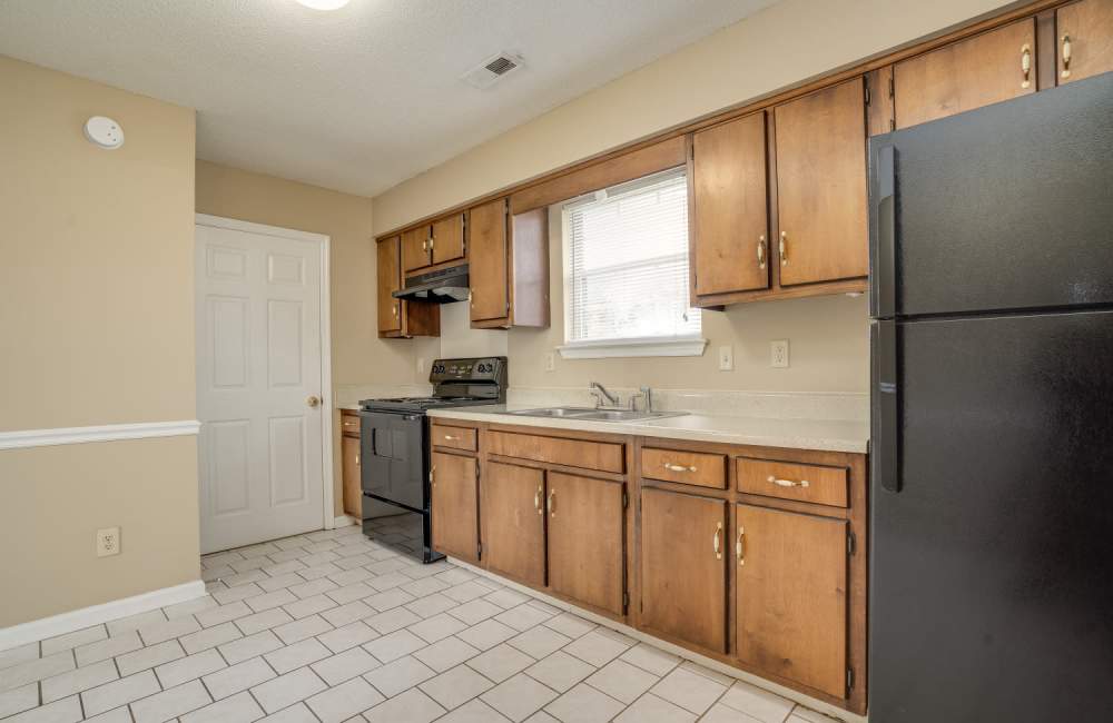 Kitchen and bar with appliances including refrigerator, microwave, oven, and cupboard storage at Spring Hill Apartments in Ringgold. GA