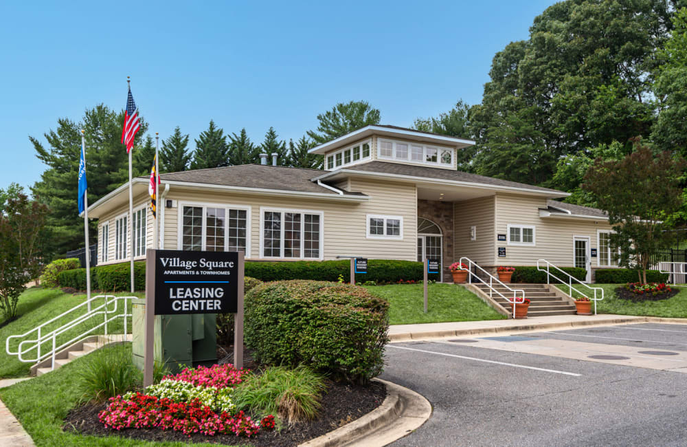 Exterior of leasing office with sign and flag pole at Village Square Apartments & Townhomes in Glen Burnie, Maryland
