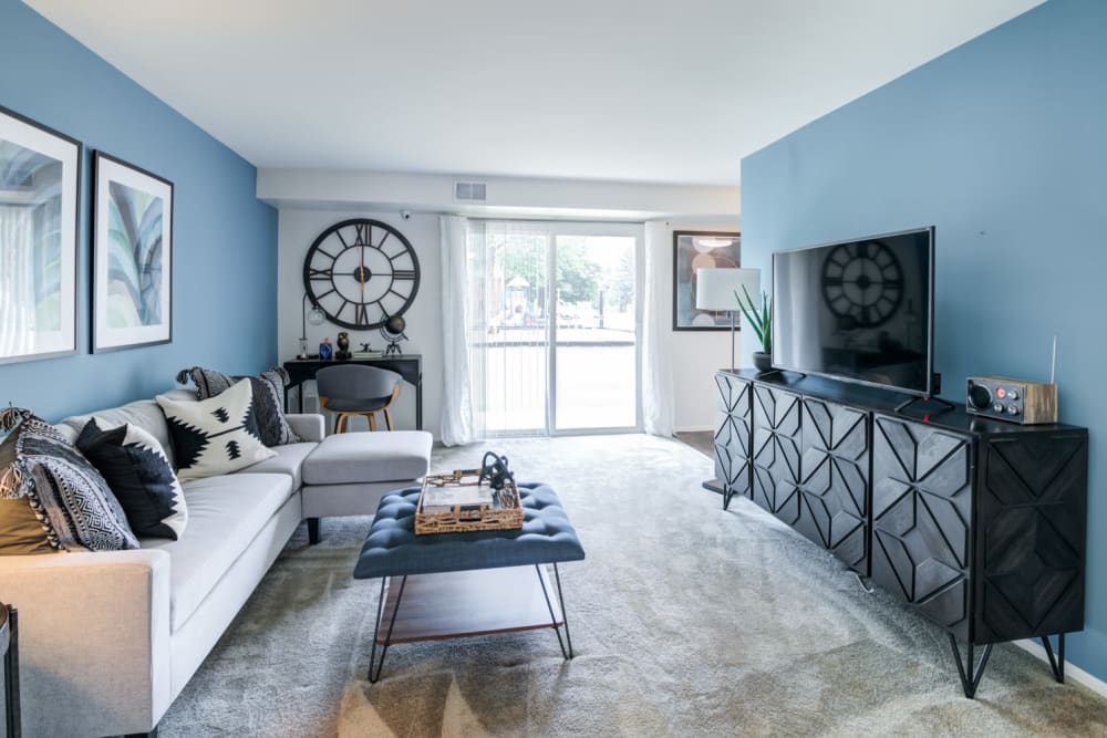 Staged living room with wall to wall carpeting and sliding door leading to patio