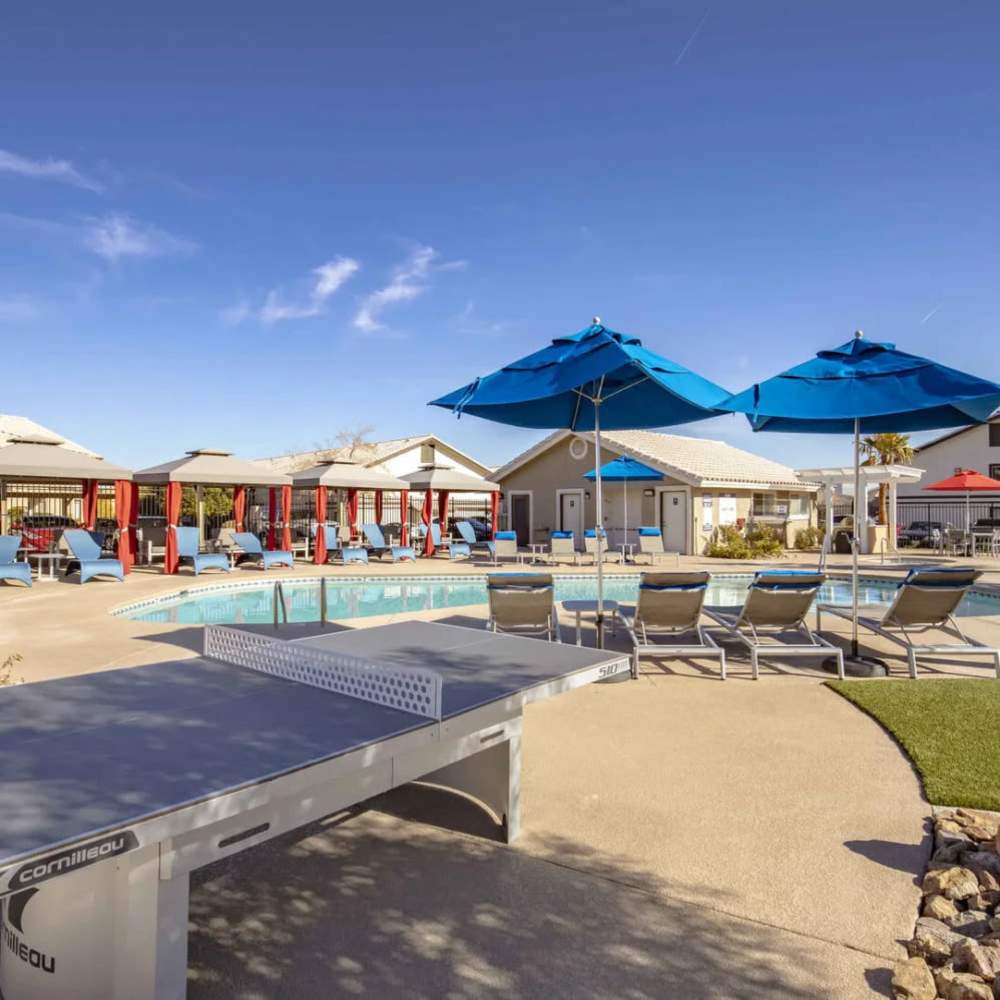 Dog-Friendly Apartments in Spring Valley, NV - Vida Las Vegas - Swimming Pool With Blue Umbrellas, Lounge Chairs, Covered Cabanas, And Outdoor Ping Pong Table.