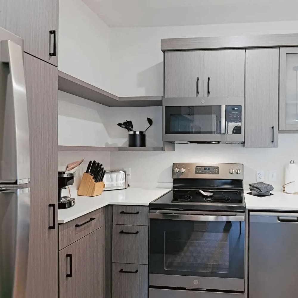 Modern kitchen with stainless steel appliances, granite countertops, and storage cabinetry at WaterWalk Boise - Meridian in Meridian, Idaho